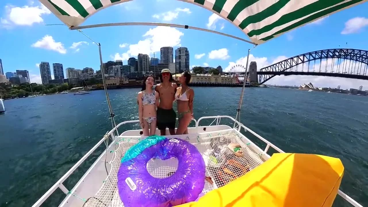 A group standing on Capri's bow with the Harbour Bridge and city behind